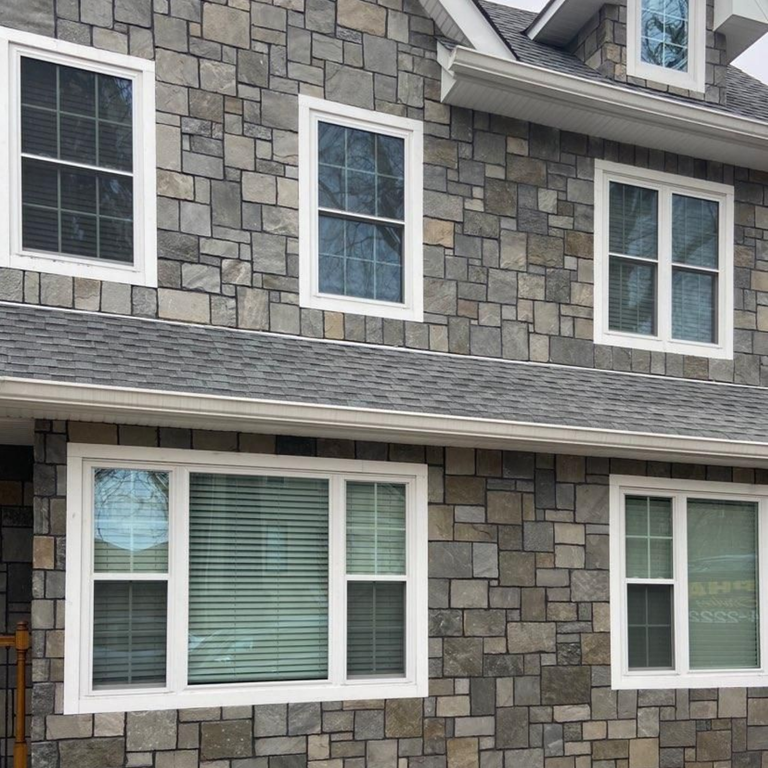 Feature image for Alpine Gray Quartzite. The image shows this material being used for full bed veneer and thin veneer. The dominant color shown is gray; with black, brown, green, purple and tan secondaries. Exhibits 