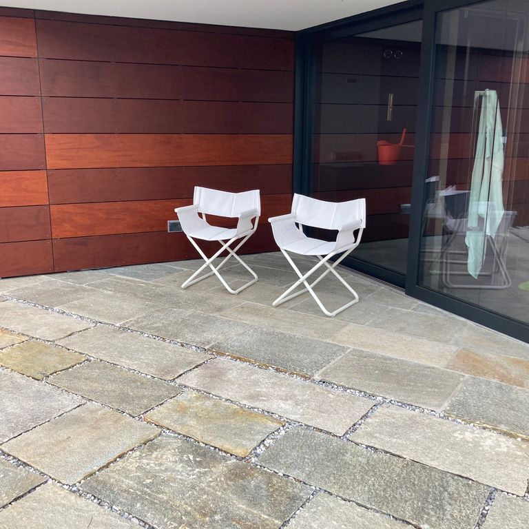 Application image for Pietra Italia Full Color Gneiss. The image shows this material being used in a patio pavers application. The surface finish shown is natural cleft. Dominant colors shown are beige and gray. The color mix creates a warm feeling.