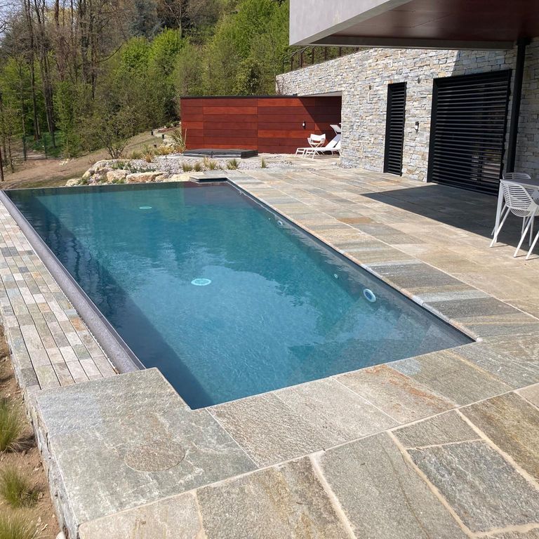 Application image for Pietra Italia Full Color Gneiss. The image shows this material being used for pool coping and patio pavers. The surface finish shown is natural cleft. Dominant colors shown are beige, gray and tan. The color mix creates a warm feeling. Regular, linear and random color patterns.