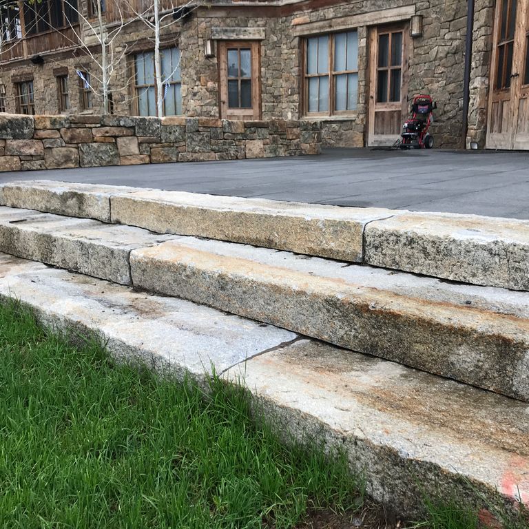 Application image for Reclaimed First Generation Granite Curbstone. The image shows this material being used in a monolithic steps application. This is a building and landscape stone for indoor and outdoor commercial and residential applications. Suitable for general use, freeze-thaw conditions, low heat absorption surfaces, high traffic areas and low slipperiness surfaces situations. Moderate to higher on the price spectrum.