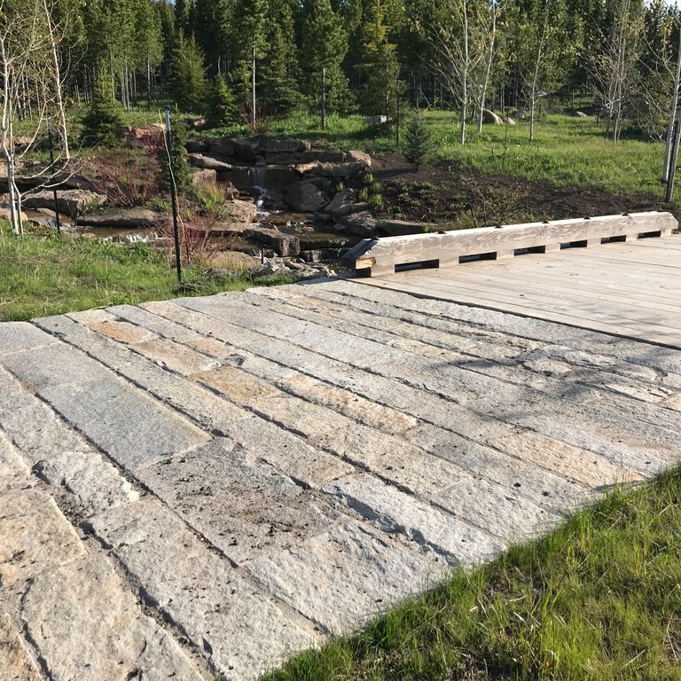 The image shows this material being used in a driveway pavers application. Dominant colors shown are beige, gray and tan; with an orange/rust secondary. Regular color pattern.