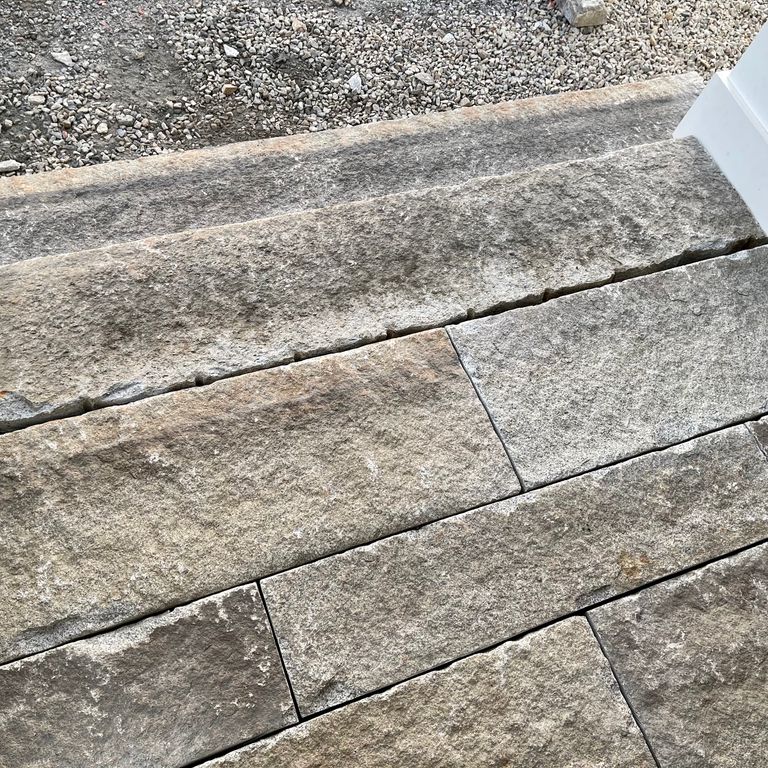The image shows this material being used in a monolithic steps application. The dominant color shown is gray; with beige, black, brown and tan secondaries. The color mix creates a warm feeling. Regular color pattern.