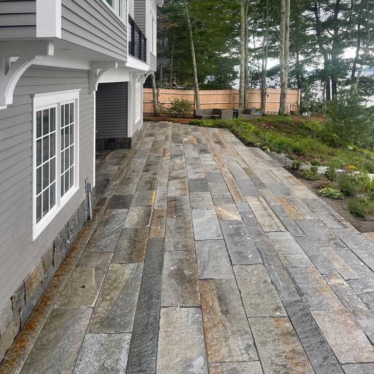 Application image for Reclaimed Third Generation Granite Curbstone. The image shows this material being used in a patio pavers application. The surface finish shown is . Dominant colors shown are gray and orange/rust. The color mix creates a warm feeling. Regular and fine speckled color patterns.