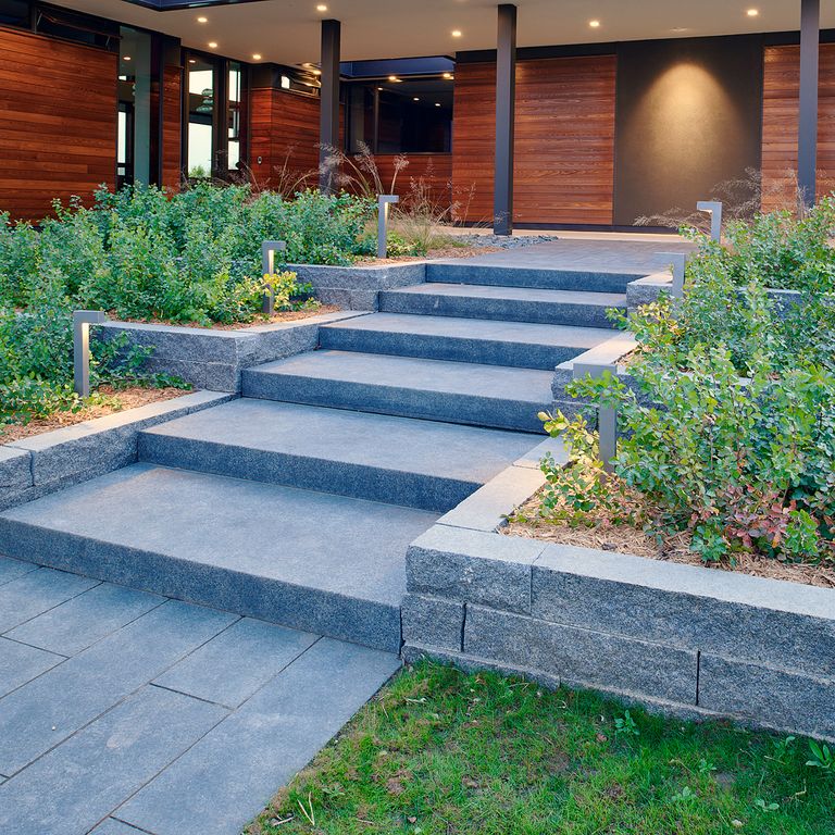 Application image for Midwest Superior Northern Granite. The image shows this material being used for landscape wallstone, path pavers and monolithic steps. The surface finish shown is flamed. Dominant colors shown are blue and gray. The color mix creates a cool feeling.
