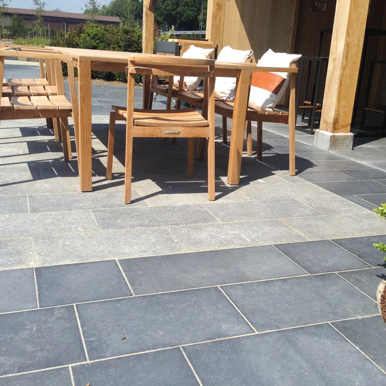 Application image for Kilkenny Limestone. The image shows this material being used in a patio pavers application. The surface finish shown is flamed. Dominant colors shown are blue and gray; with a white secondary. The color mix creates a cool feeling.