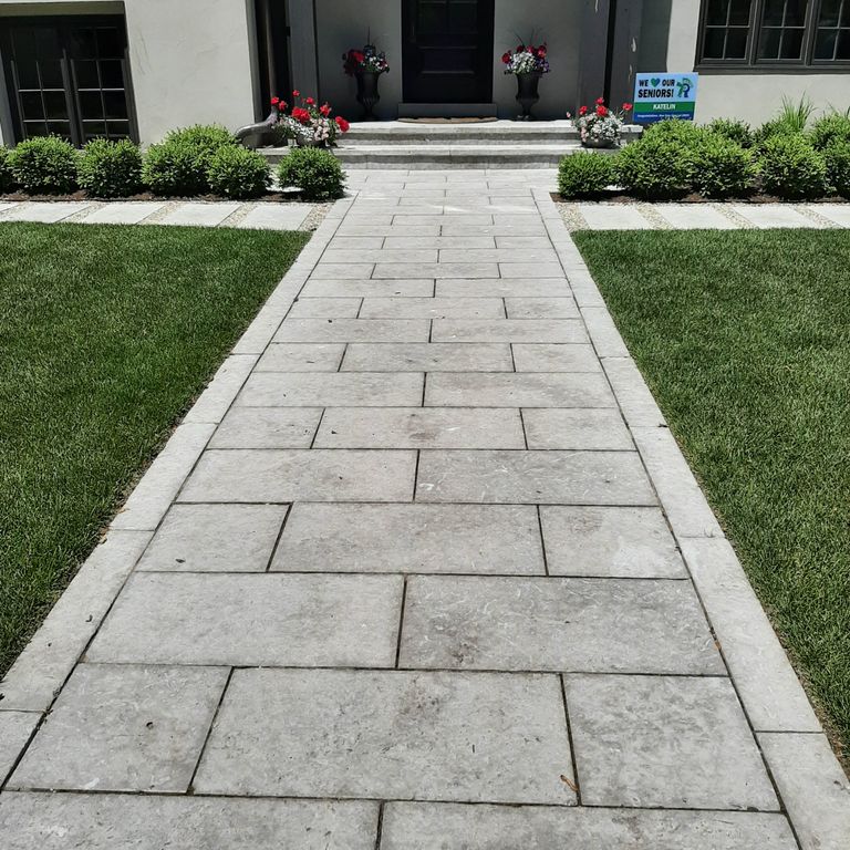 Application image for Limestone - Madison. The image shows this material being used for landscape curbing & edging, path pavers and treads. The surface finish shown is flamed. The dominant color shown is gray; with beige, blue, purple, white and cream secondaries. The color mix creates a cool feeling. Regular and cloudy color patterns. Contains mineral inclusions.