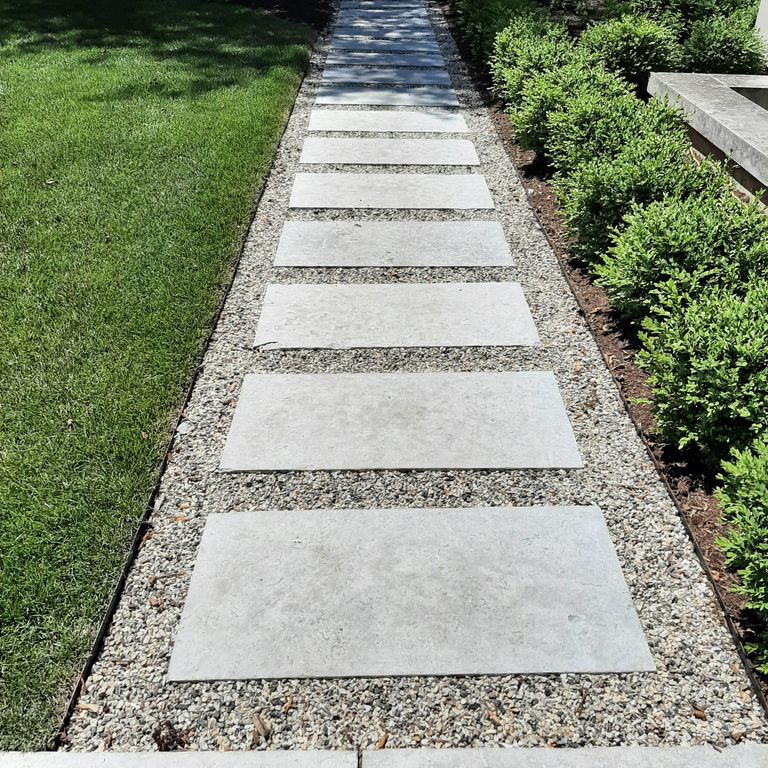 Application image for Madison Limestone. The image shows this material being used in a path pavers application. The surface finish shown is flamed. Dominant colors shown are beige and gray; with purple and cream secondaries. The color mix creates a cool feeling. Regular color pattern.