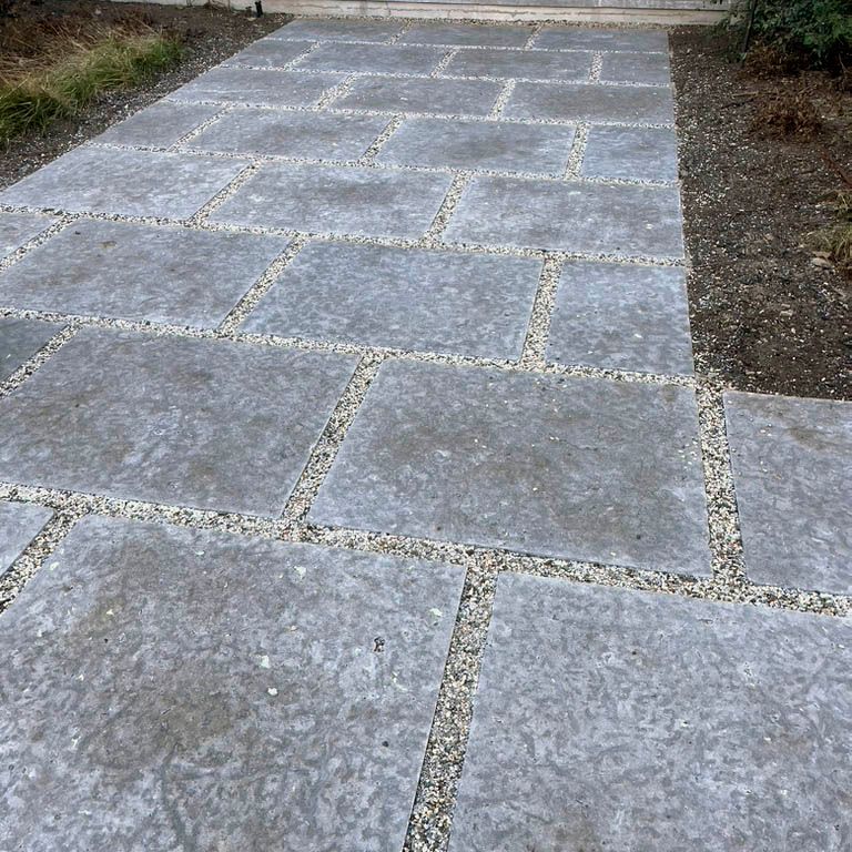 Application image for Madison Limestone. The image shows this material being used in a path pavers application. The surface finish shown is flamed. Dominant colors shown are blue and gray. The color mix creates a cool feeling. Regular and blotched color patterns. Contains voids.