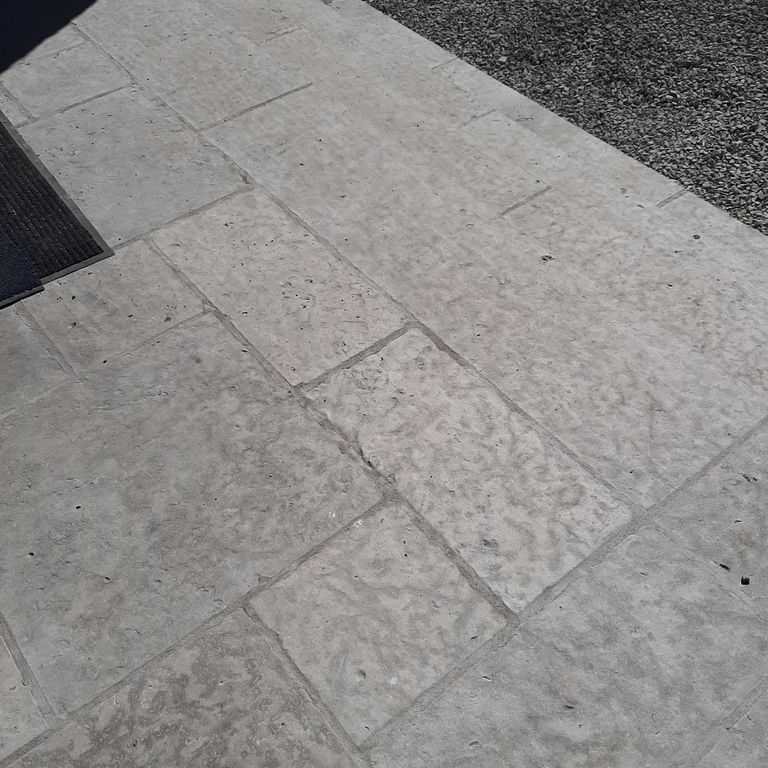 Application image for Rustic Gray Limestone. The image shows this material being used for patio pavers and treads. The surface finish shown is flamed. The dominant color shown is gray; with a purple secondary. The color mix creates a cool feeling. Cloudy color pattern.