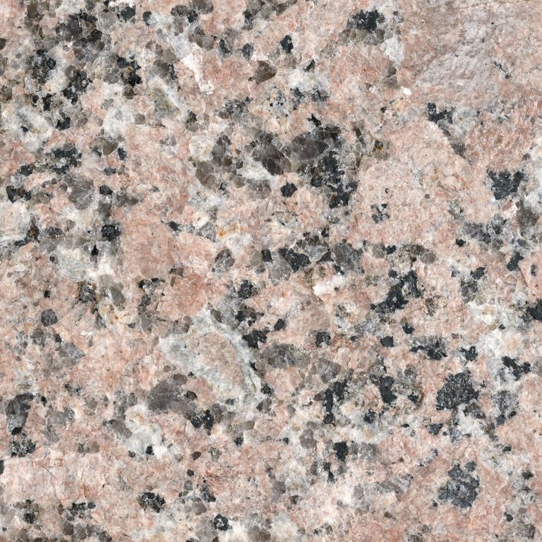 Feature image for Sunset Red® Granite. The surface finish shown is flamed. Dominant colors shown are beige and gray; with brown, orange/rust, pink, purple, white, yellow and tan secondaries. The color mix creates a warm feeling. Coarse speckled color pattern. Contains some mica and mineral inclusions.