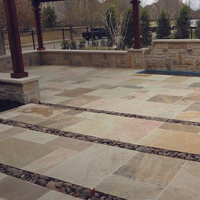 Feature image for Golden Fossil Sandstone. The image shows this material being used for patio pavers, full bed veneer and thin veneer. The surface finish shown is natural cleft. The dominant color shown is green; with brown, gray, orange/rust and tan secondaries. The color mix creates a warm feeling. Regular and streaked color patterns.