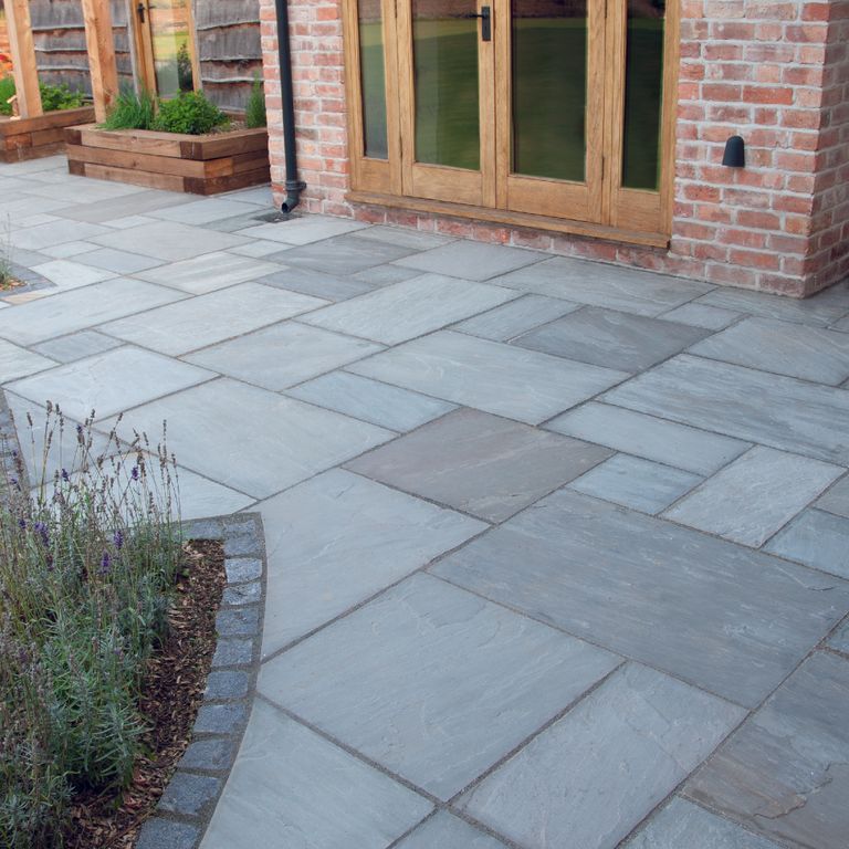 Best close-up image for Promenade Sandstone. The image shows this material being used for path pavers and patio pavers. The surface finish shown is natural cleft. Dominant colors shown are blue and gray. The color mix creates a cool feeling. Regular and linear color patterns.