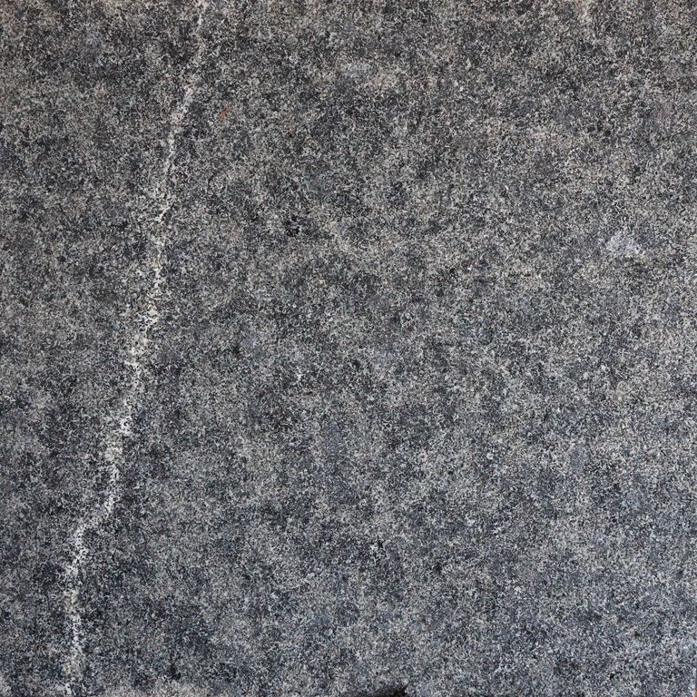 Feature image for Addison Black Granite. The surface finish shown is a combination of brushed and flamed. Dominant colors shown are black and gray; with blue, brown, green, purple and white secondaries. The color mix creates a cool feeling. Regular and fine speckled color patterns. Contains some mica and mineral inclusions.