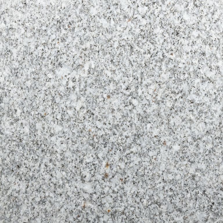 Feature image for Barre Gray Granite. The surface finish shown is flamed. Dominant colors shown are gray and white; with beige, pink, purple, white and cream secondaries. The color mix creates a cool feeling. Fine speckled color pattern. Contains some mica and mineral inclusions.