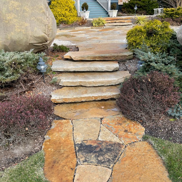 Feature image for South Bay Quartzite. The image shows this material being used for path pavers, patio pavers and monolithic steps. The surface finish shown is a combination of split-face with flat plane and split-face with rough plane. Dominant colors shown are beige, orange/rust and tan; with brown, gray and cream secondaries. The color mix creates a warm feeling.