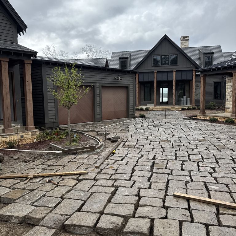 Application image for Reclaimed New England Granite - Bridge Squares. The image shows this product being used in a driveway pavers application. The surface finish shown is . The dominant color shown is gray.