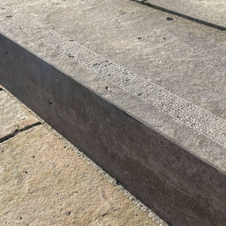 Best close-up image for Bavarian Dolomite Gray Limestone - Steps & Treads. The image shows this product being used for landscape curbing & edging, driveway pavers and patio pavers. The surface finish shown is flamed. Dominant colors shown are gray and tan. The color mix creates a warm feeling. Regular and cloudy color patterns.