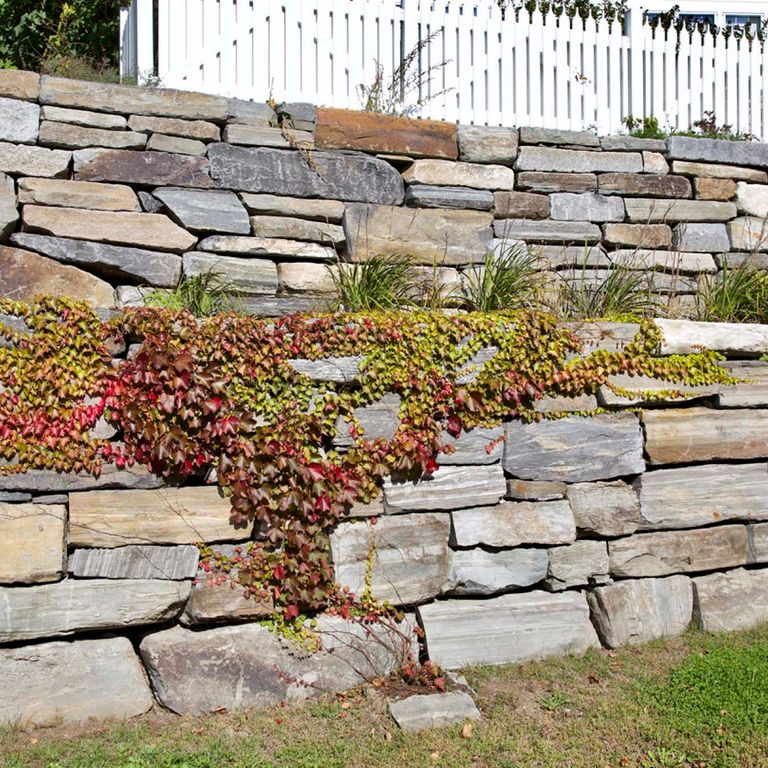 Application image for Mystic Mountian Granite - Natural Wallstone. The image shows this product being used in a landscape wallstone application. The dominant color shown is gray. The color mix creates a warm feeling.