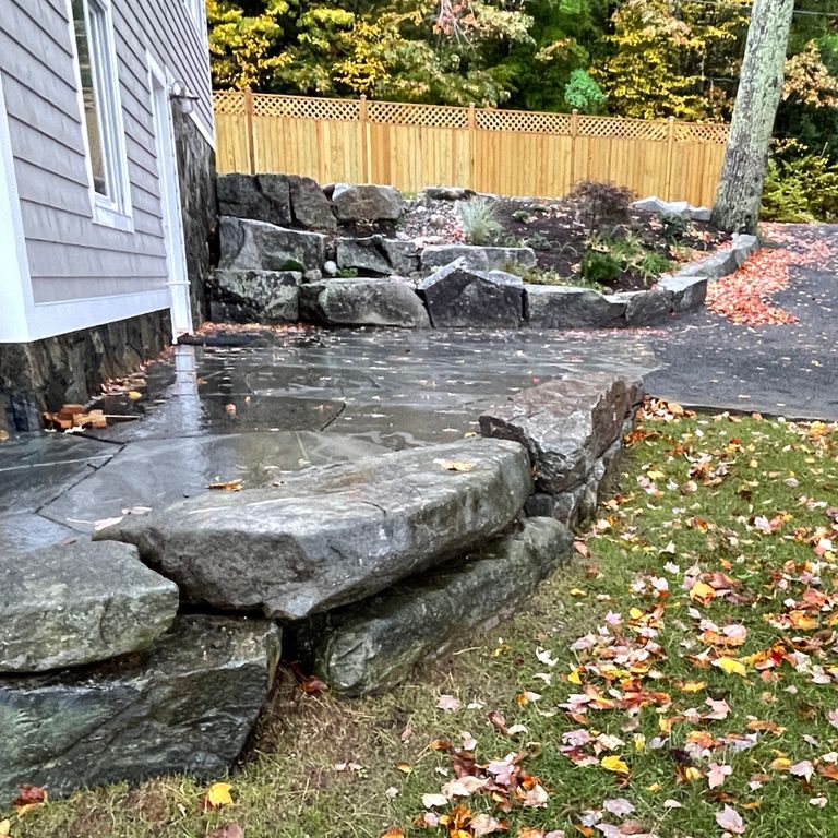 Application image for Mystic Mountain Natural - Wallstone. The image shows this product being used in a landscape wallstone application. The surface finish shown is natural. The dominant color shown is gray; with green and white secondaries. The color mix creates a cool feeling. Regular color pattern.