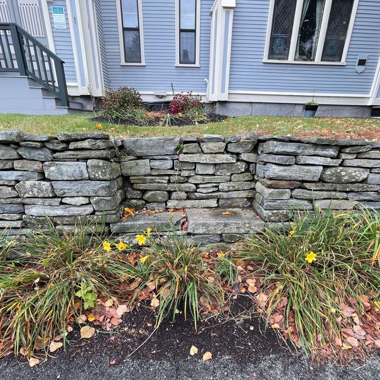 Application image for Mystic Mountain Natural - Wallstone. The image shows this product being used in a landscape wallstone application. The surface finish shown is split-face. The dominant color shown is gray; with blue, green and white secondaries. The color mix creates a cool feeling. Regular and streaked color patterns.