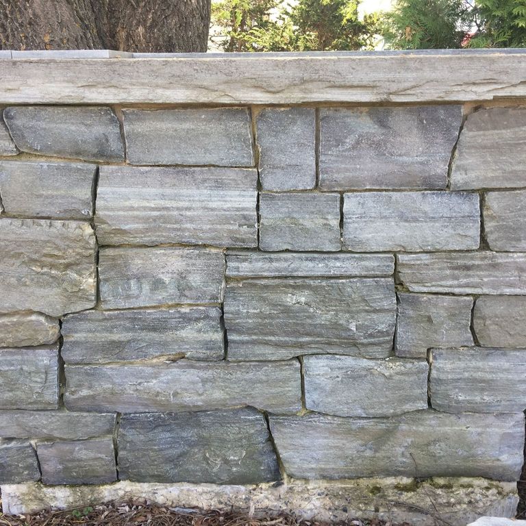 Application image for Granite - Mystic Mountain- Splitface Veneer. The image shows this product being used in a full bed veneer application. Dominant colors shown are green, gray and white; with green, purple and white secondaries. Exhibits 