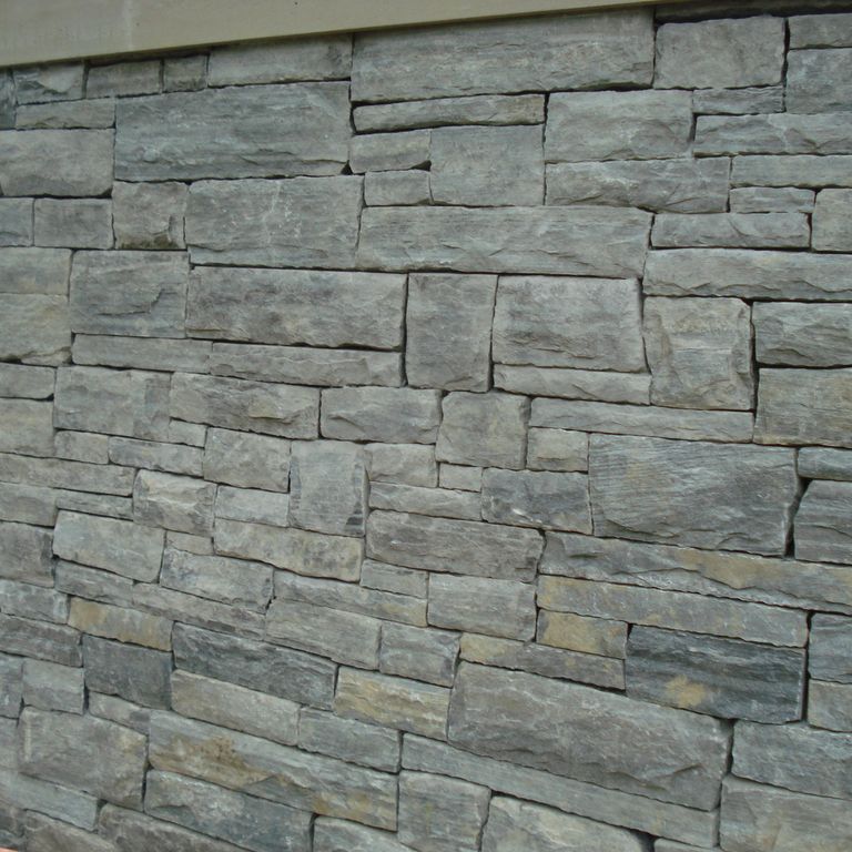 Application image for Granite - Mystic Mountain- Splitface Veneer. The image shows this product being used in a full bed veneer application. Dominant colors shown are green and gray. Exhibits 