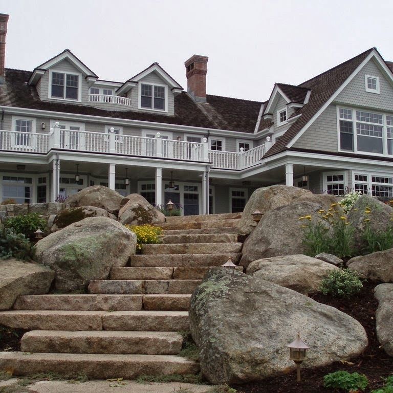 Application image for New England Fieldstone - Boulders. The image shows this product being used for landscape boulders & ledge, landings, monolithic steps and treads. The surface finish shown is weathered. The dominant color shown is gray. The color mix creates a warm feeling.