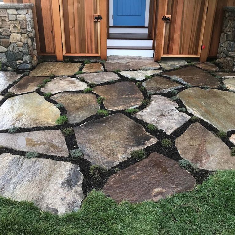 Application image for New England Fieldstone Oversized Pavers. The image shows this product being used in a patio pavers application. The surface finish shown is natural cleft. Dominant colors shown are brown and gray; with orange/rust and tan secondaries. Exhibits 