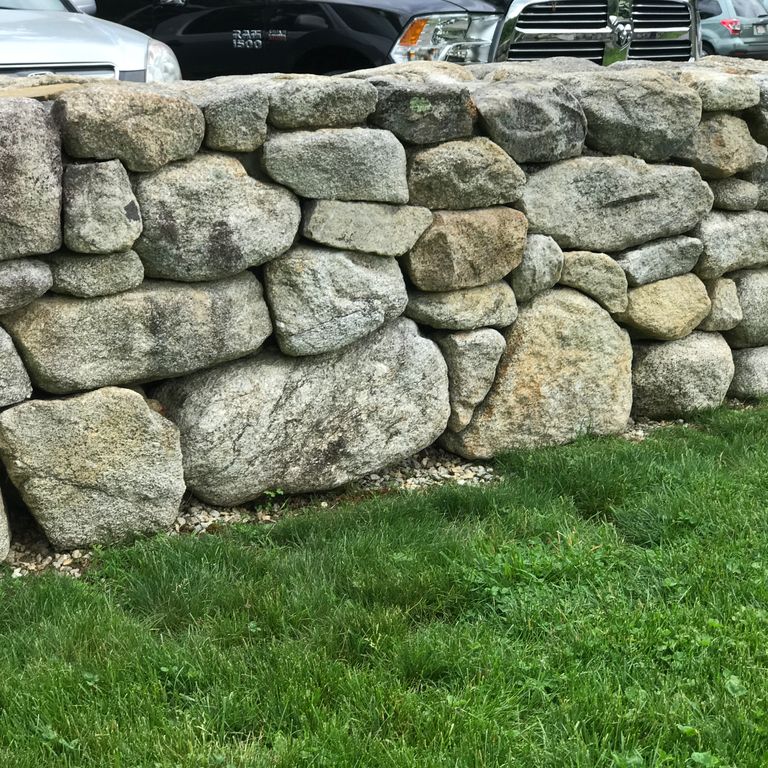 Application image for New England Fieldstone - Wallstone Run Mix. The image shows this product being used in a landscape wallstone application. The surface finish shown is weathered. The dominant color shown is gray.