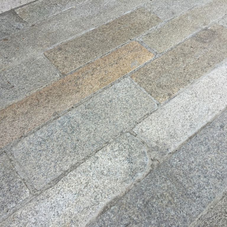 Best close-up image for Reclaimed Footworn Granite - Plank Pavers. The image shows this product being used for driveway pavers, path pavers and patio pavers. The surface finish shown is . The dominant color shown is gray; with beige, white and tan secondaries. Fine speckled and speckled color patterns.