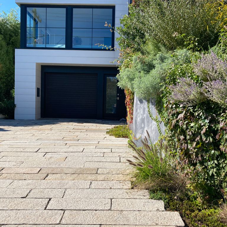 Application image for Reclaimed Footworn Granite - Plank Pavers. The image shows this product being used in a driveway pavers application. The surface finish shown is . Dominant colors shown are beige, gray and tan. The color mix creates a warm feeling. Speckled color pattern.