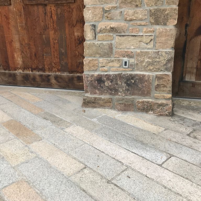 Application image for Reclaimed Footworn Granite - Plank Pavers. The image shows this product being used in a driveway pavers application. The surface finish shown is . Dominant colors shown are beige and gray. The color mix creates a warm feeling. Speckled color pattern.