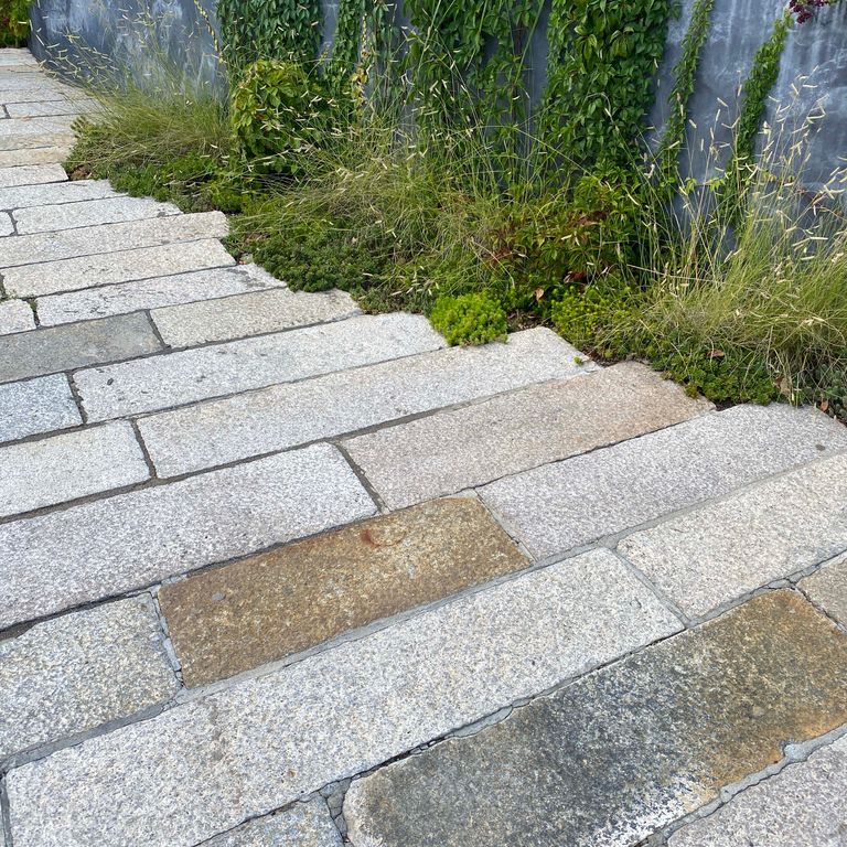 Application image for Reclaimed Footworn Granite - Plank Pavers. The image shows this product being used in a driveway pavers application. The surface finish shown is . The dominant color shown is gray. The color mix creates a warm feeling. Regular, speckled and blotched color patterns.