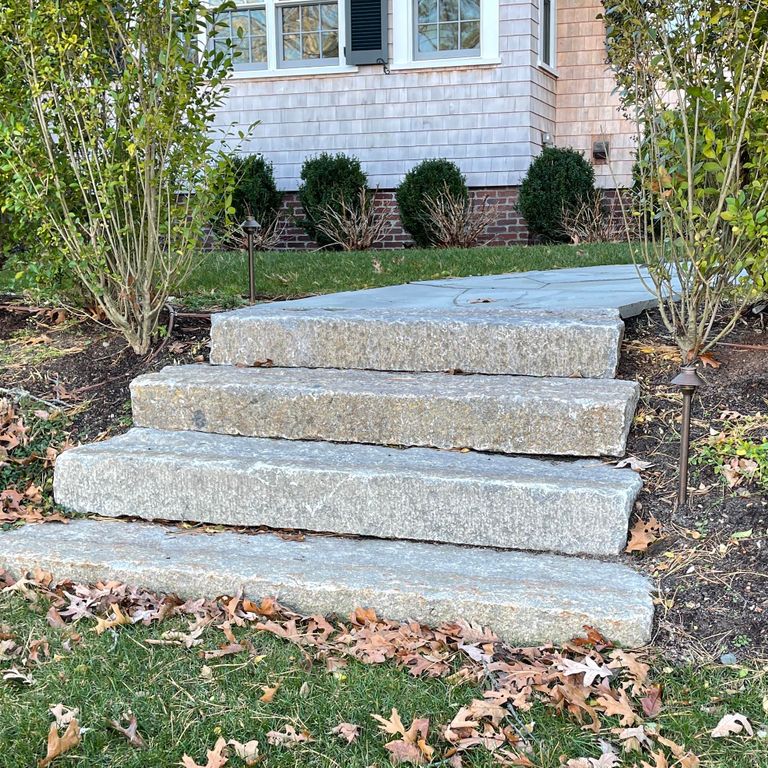 Application image for Reclaimed First Generation Granite Curbstone Steps - Textured Riser and Tread. The image shows this product being used in a monolithic steps application. This is a landscape stone for outdoor commercial and residential applications. Suitable for general use, freeze-thaw conditions, low heat absorption surfaces, high traffic areas and low slipperiness surfaces situations. Higher to high on the price spectrum.