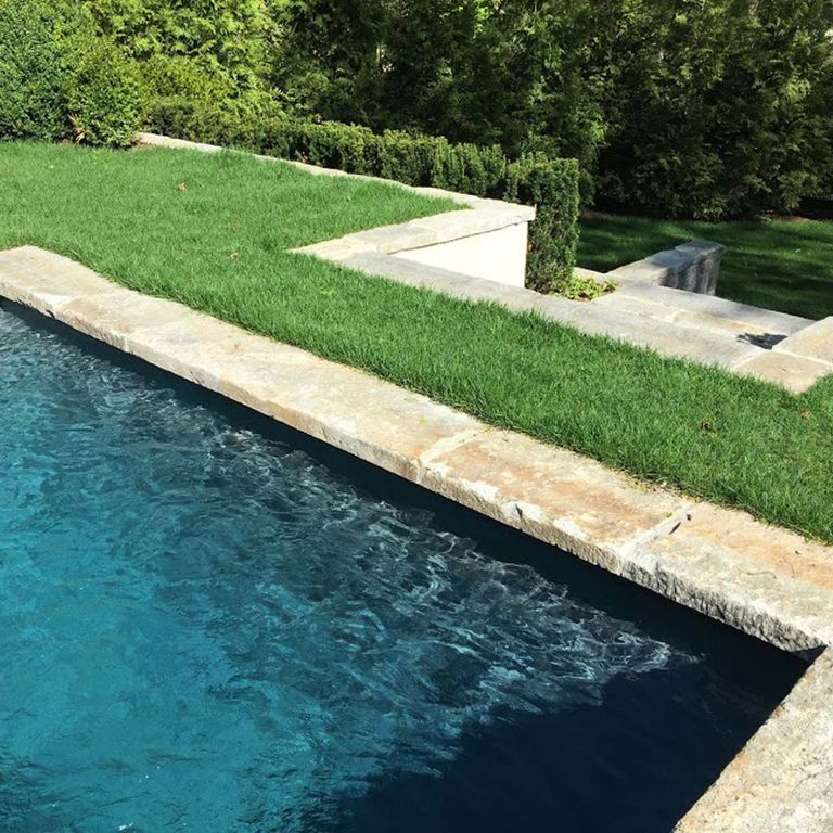 Application image for Reclaimed Granite Curbstone - Pool Coping. The image shows this product being used in a pool coping application. The surface finish shown is . Dominant colors shown are beige, gray and tan; with gray, orange/rust, white and cream secondaries. The color mix creates a warm feeling. Blotched, random and cloudy color patterns.