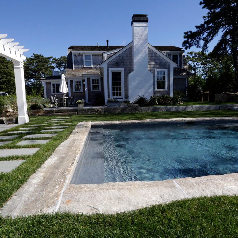 Application image for Reclaimed Granite Curbstone - Pool Coping. The image shows this product being used in a pool coping application. The surface finish shown is a combination of split-face with flat plane, weathered and worn. Dominant colors shown are beige and gray; with white, tan and cream secondaries. The color mix creates a warm feeling. Regular and speckled color patterns.