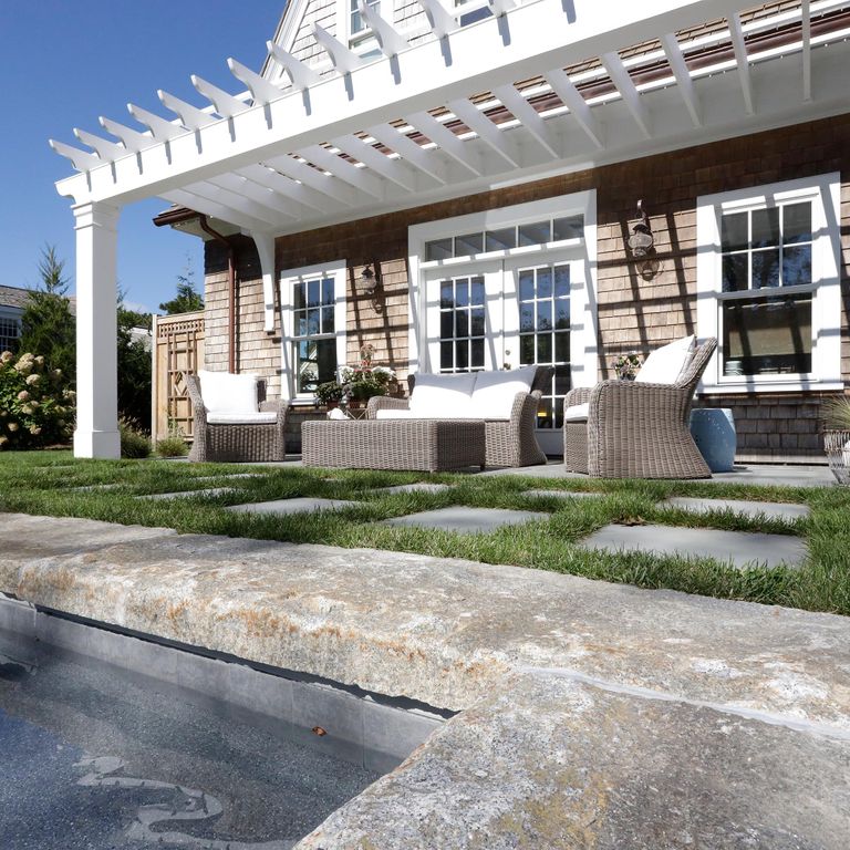 Application image for Reclaimed Granite Curbstone - Pool Coping. The image shows this product being used in a pool coping application. The surface finish shown is a combination of split-face with flat plane, weathered and worn. The dominant color shown is gray; with beige, orange/rust, white, tan and cream secondaries. The color mix creates a warm feeling. Regular and speckled color patterns.