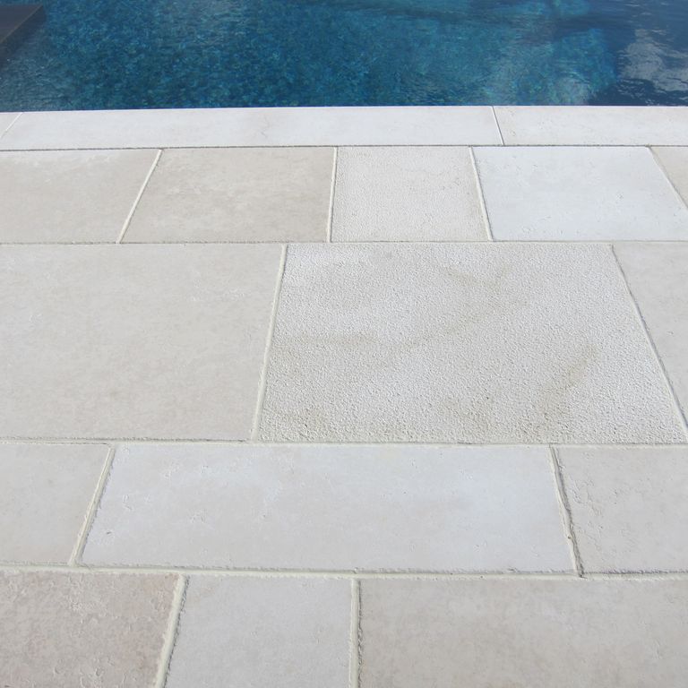 Application image for Mountain Hard Limestone Beige - Dimensional Cut Pavers. The image shows this product being used for patio pavers and pool deck pavers. The surface finish shown is a combination of bush hammered and flamed. The dominant color shown is beige; with white and cream secondaries. The color mix creates a warm feeling. Regular color pattern.