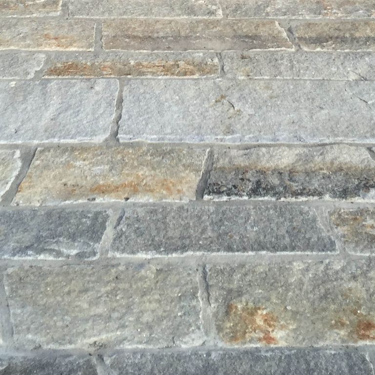 Close-up image for Reclaimed Second Generation Granite Curbstone Plank Pavers. The surface finishes shown are weathered and worn. The dominant color shown is gray; with beige, blue, green, orange/rust, white and tan secondaries. Exhibits 