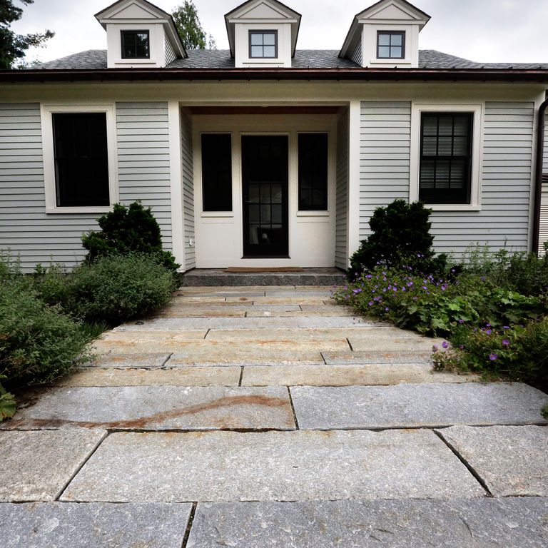 Application image for Reclaimed Third Generation Granite Curbstone Plank Pavers. The image shows this product being used in a path pavers application. The surface finish shown is a combination of split-face with flat plane, weathered and worn. Dominant colors shown are beige and gray; with blue, brown, orange/rust, purple, white, tan and cream secondaries. The color mix creates a warm feeling. Fine speckled and blotched color patterns.
