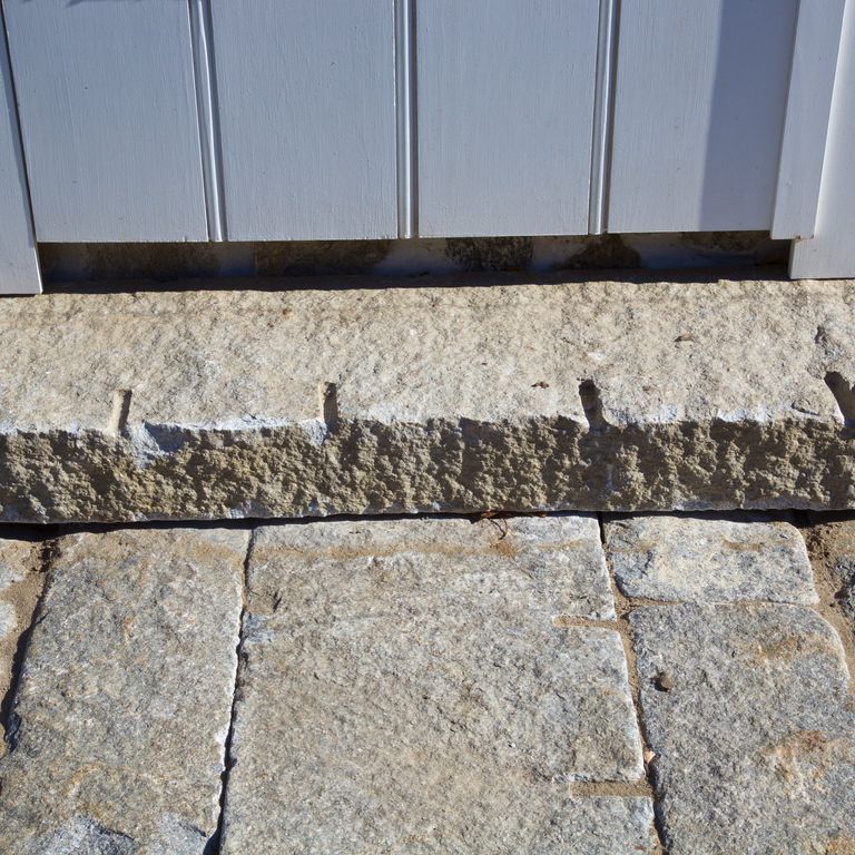 Feature image for Reclaimed Second Generation Granite Curbstone Steps - Split Face Riser. The image shows this product being used in a monolithic steps application. The dominant color shown is gray; with beige, brown, white and tan secondaries. Speckled color pattern.