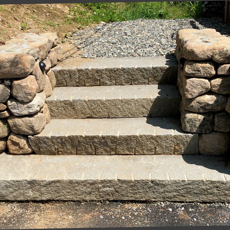 Application image for Reclaimed Second Generation Granite Curbstone Steps - Split Face Riser. The image shows this product being used in a monolithic steps application. This is a landscape stone for outdoor commercial and residential applications. Suitable for general use, freeze-thaw conditions, low heat absorption surfaces, high traffic areas and low slipperiness surfaces situations. Higher to high on the price spectrum.