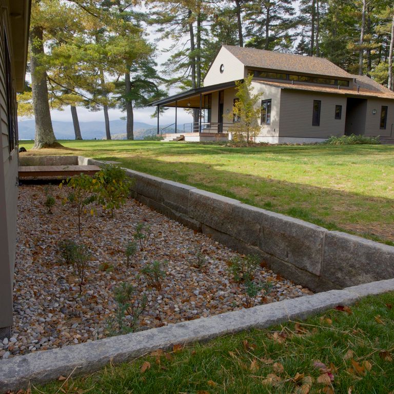 Feature image for Reclaimed First Generation Granite Curbstone Edging. The image shows this product being used in a landscape curbing & edging application. Dominant colors shown are brown and gray. Exhibits 