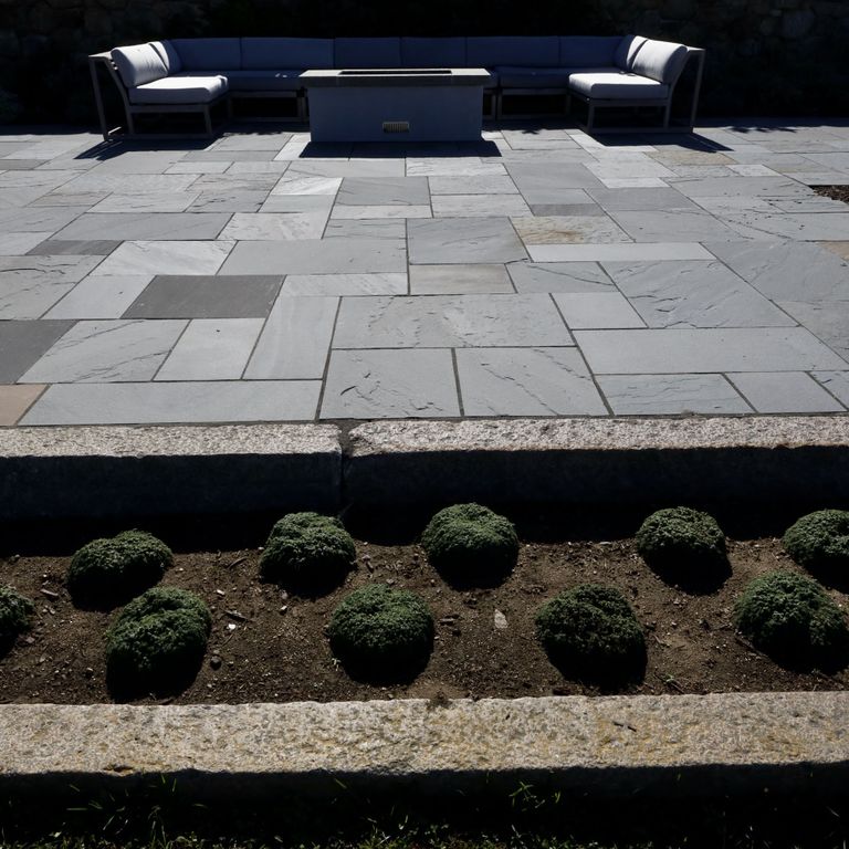 Application image for Reclaimed First Generation Granite Curbstone - Edging. The image shows this product being used in a landscape curbing & edging application. The surface finish shown is a combination of weathered and worn. The dominant color shown is brown; with a gray secondary.