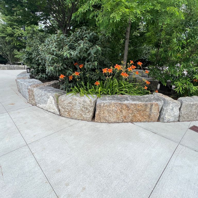 Application image for Granite - Reclaimed Block Wallstone - Block Mix. The image shows this product being used for landscape wallstone and landscape curbing & edging. The dominant color shown is gray. The color mix creates a warm feeling.