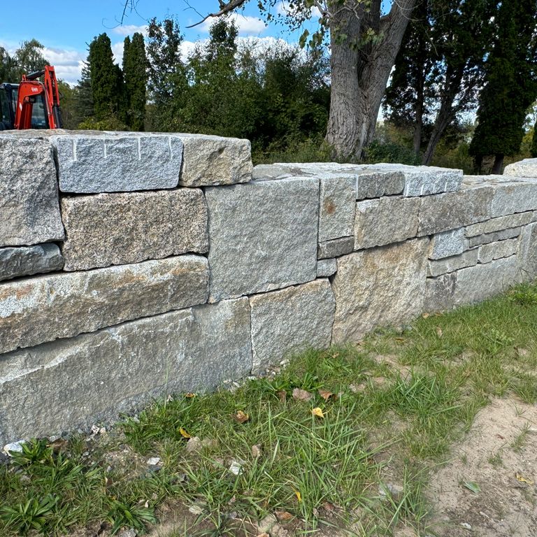 Application image for Granite - Reclaimed Block Wallstone - Block Mix. The image shows this product being used in a landscape wallstone application. The dominant color shown is gray.
