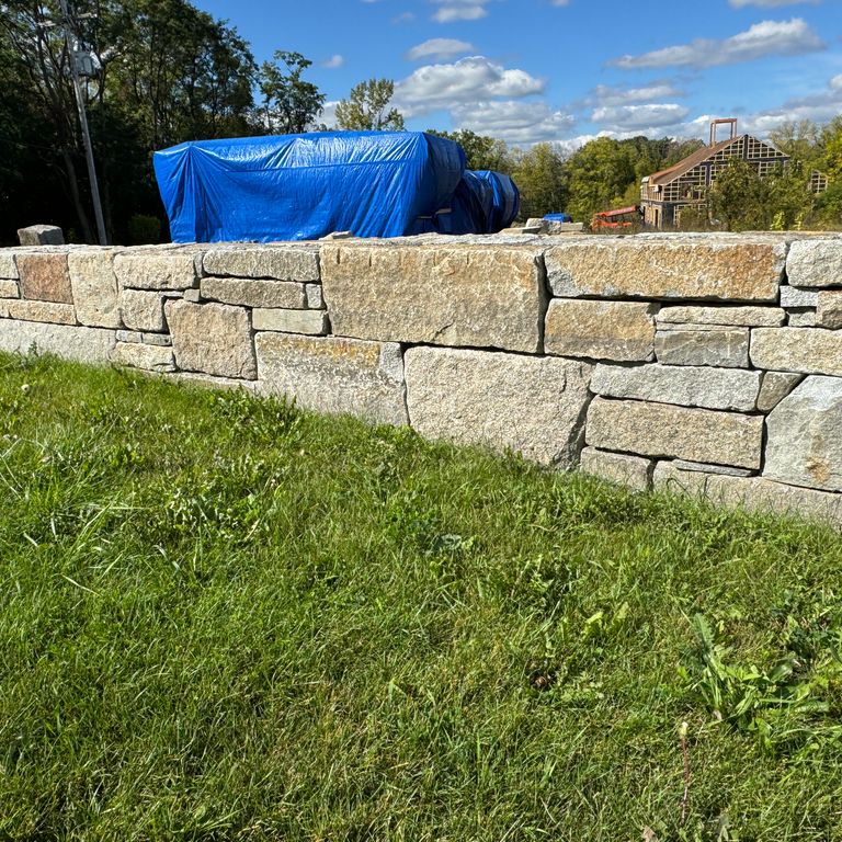 Application image for Granite - Reclaimed Block Wallstone - Block Mix. The image shows this product being used in a landscape wallstone application. The dominant color shown is gray. The color mix creates a warm feeling.