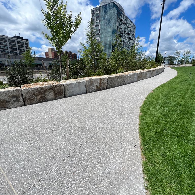 Application image for Granite - Reclaimed Block Wallstone - Block Mix. The image shows this product being used for landscape wallstone and landscape curbing & edging. The dominant color shown is gray. The color mix creates a cool feeling.