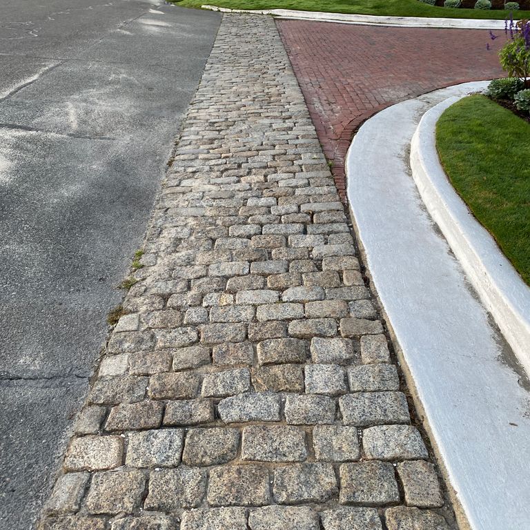 Application image for Granite - Reclaimed New England Cobblestones - Medium Pavers. The image shows this product being used in a driveway aprons application. The dominant color shown is gray.