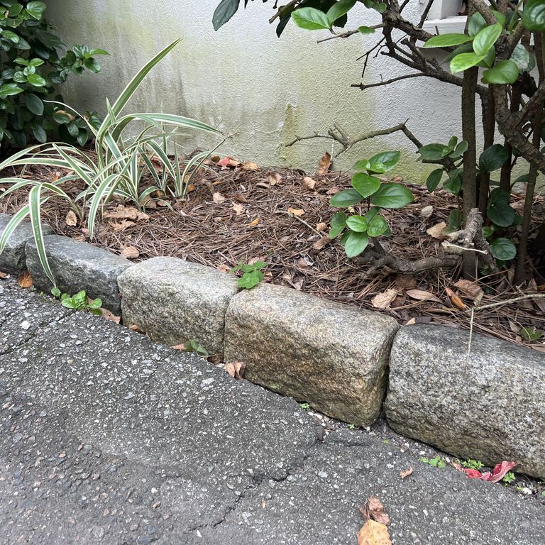 Application image for Granite - Reclaimed New England Cobblestones - Jumbo Edging. The image shows this product being used in a landscape curbing & edging application. The surface finish shown is . The dominant color shown is gray. The color mix creates a warm feeling.